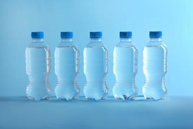 Row of plastic bottles with water on color background