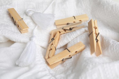 Photo of Many wooden clothespins on white garment, closeup view