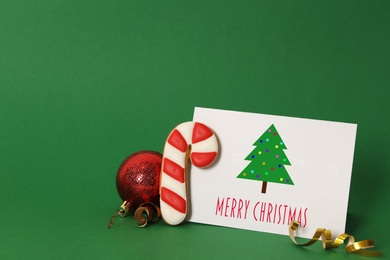 Image of Greeting card with text Merry Christmas, ball and cookie on green background