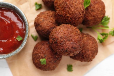 Photo of Vegan meat products. Delicious falafel balls, parsley and sauce on table, flat lay
