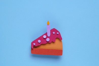 Photo of Birthday party. Paper cake with candle on light blue background, top view