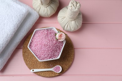 Flat lay composition with sea salt and herbal bags on pink wooden table. Space for text