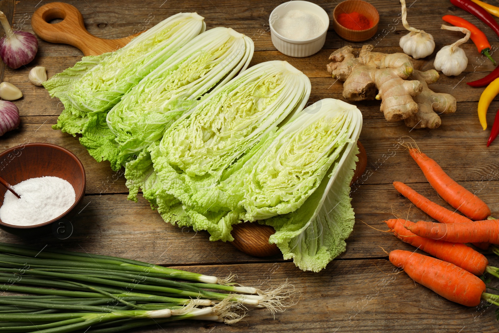 Photo of Cut fresh ripe Chinese cabbages and ingredients on wooden table