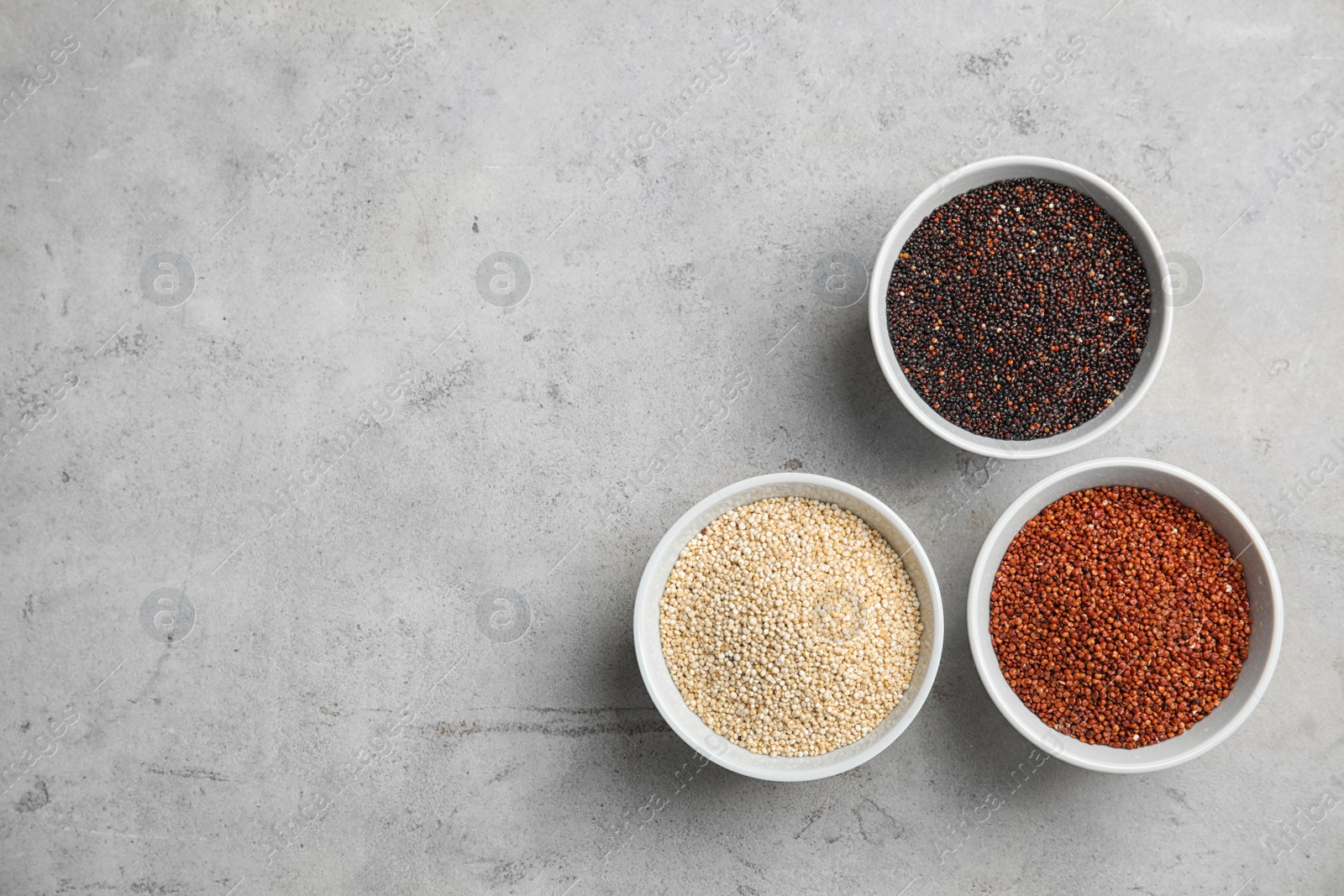 Photo of Flat lay composition with different types of quinoa and space for text on grey background