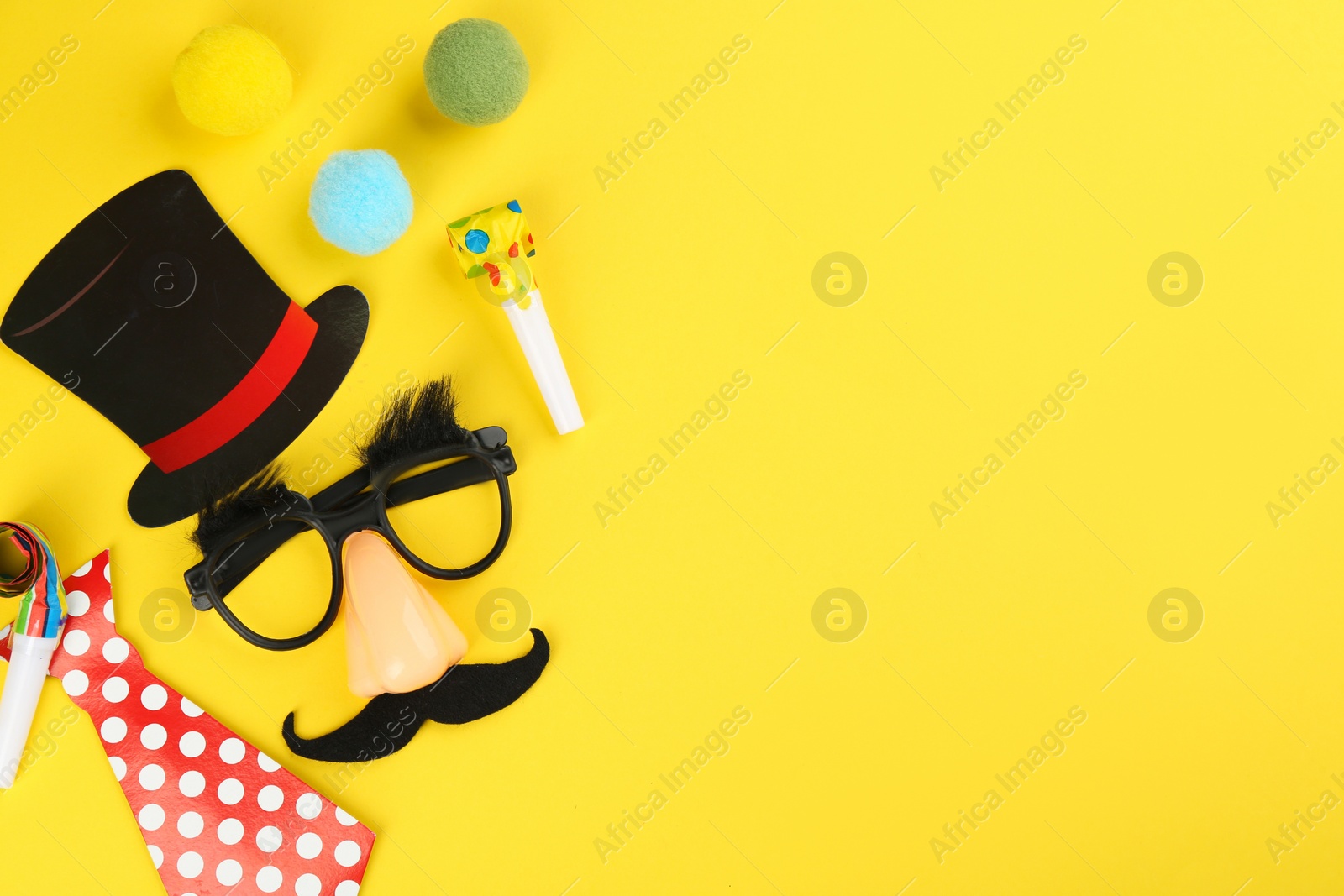 Photo of Flat lay composition with clown mask and tie on yellow background. Space for text