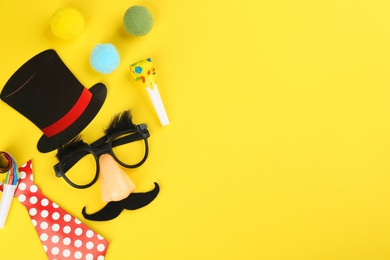 Photo of Flat lay composition with clown mask and tie on yellow background. Space for text