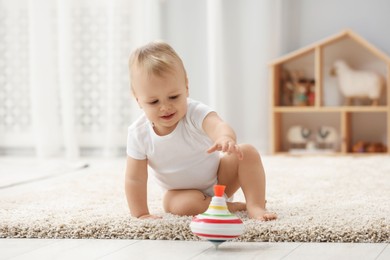 Children toys. Cute little boy playing with spinning top on rug at home