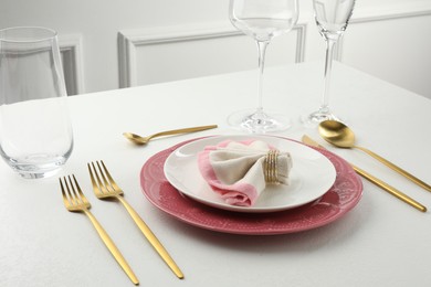 Stylish setting with cutlery, napkin and plates on white textured table