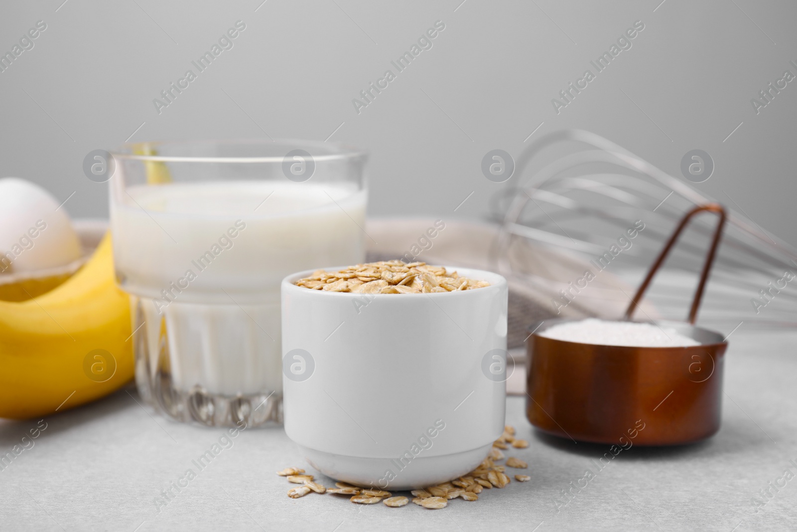 Photo of Different ingredients for cooking tasty oatmeal pancakes on grey table
