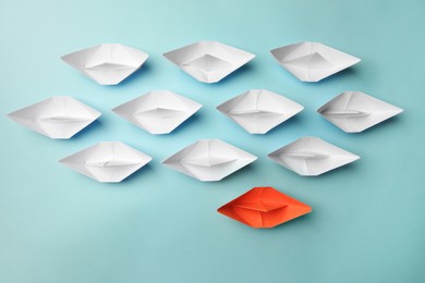 Photo of Orange paper boat among others on light background, flat lay. Uniqueness concept