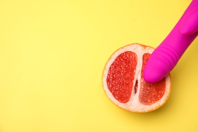 Half of grapefruit and purple vibrator on yellow background, flat lay with space for text. Sex concept