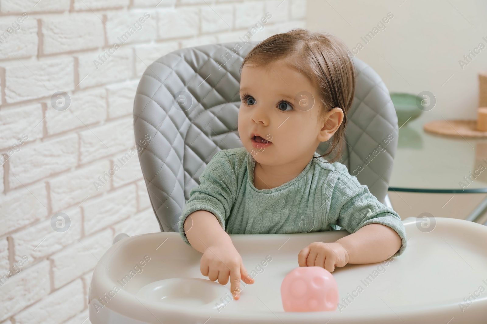 Photo of Cute little baby sitting in high chair indoors