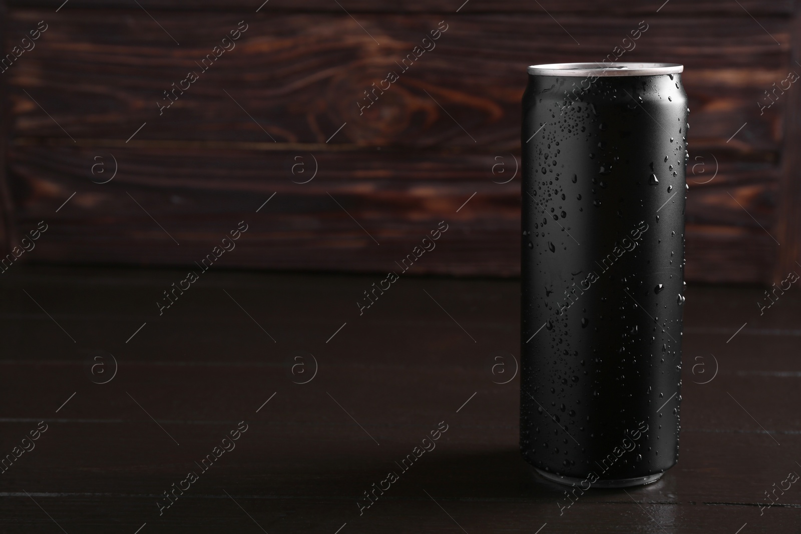 Photo of Energy drink in wet can on dark wooden table, space for text