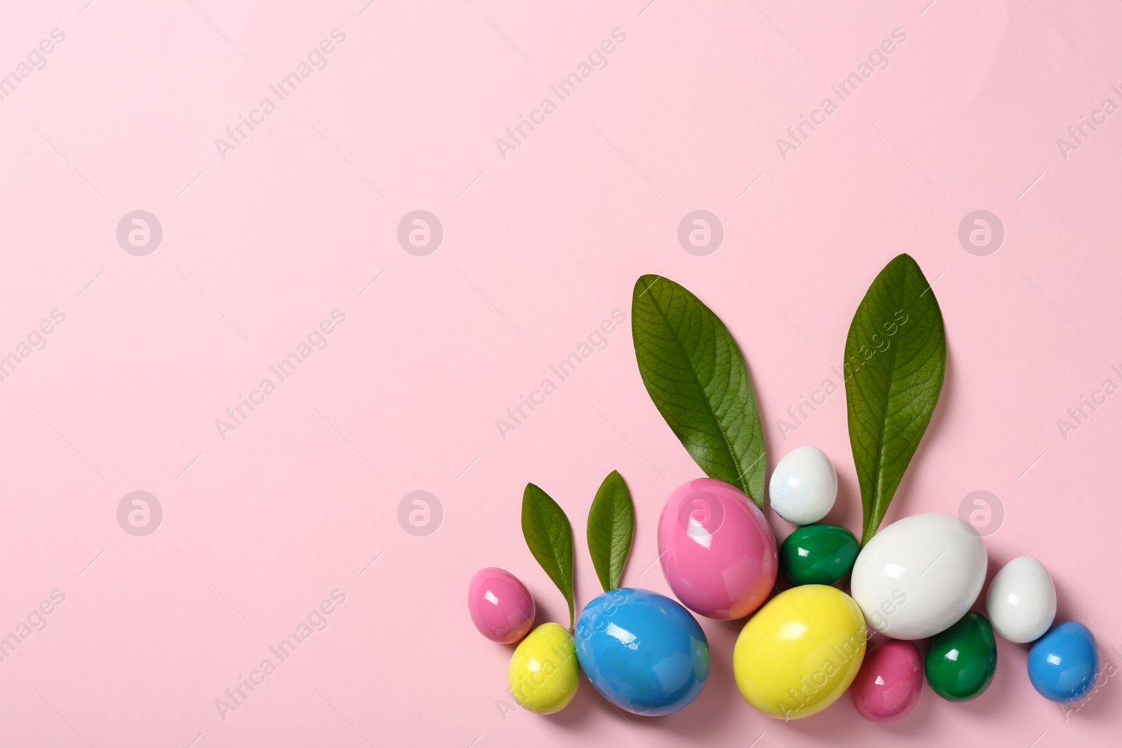 Photo of Creative flat lay composition with Easter bunny ears made of green leaves and eggs on color background, space for text