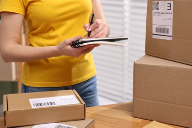 Photo of Parcel packing. Post office worker writing notes indoors, closeup