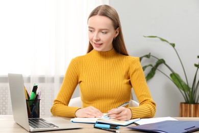 Photo of Woman taking notes at wooden table in office