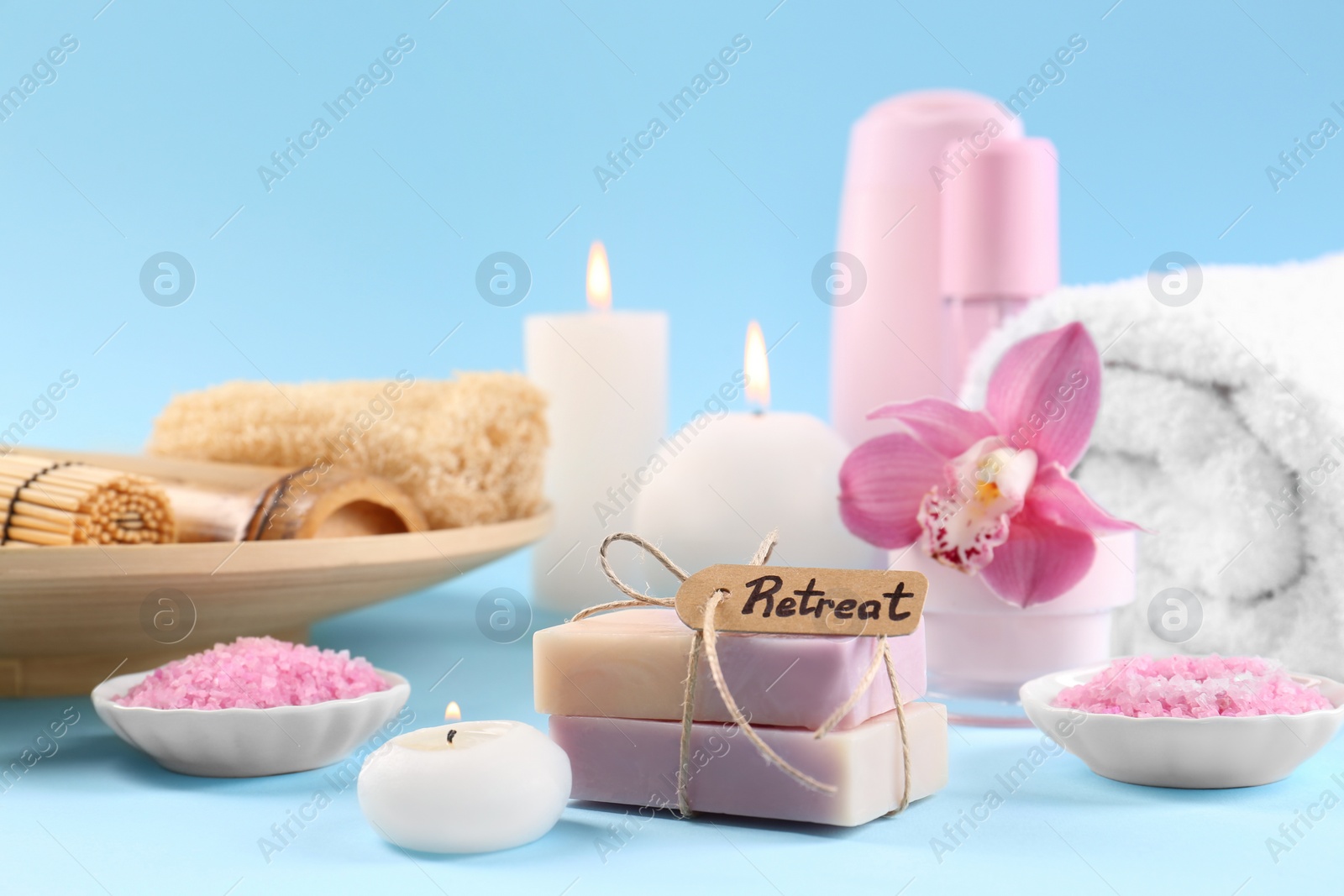 Photo of Retreat concept. Composition with different spa products, burning candles and beautiful orchid on light blue background