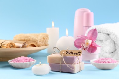 Retreat concept. Composition with different spa products, burning candles and beautiful orchid on light blue background