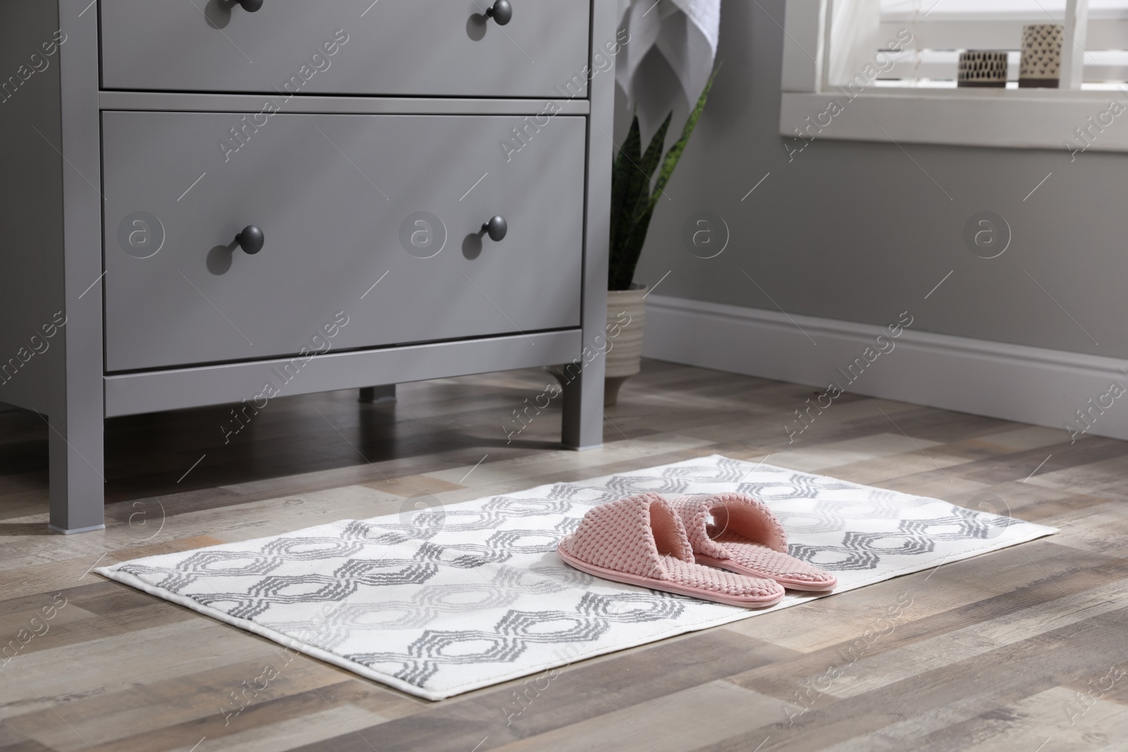 Photo of Mat with slippers near grey chest of drawers indoors