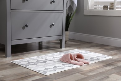 Photo of Mat with slippers near grey chest of drawers indoors