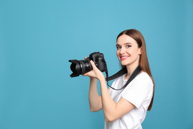 Professional photographer with modern camera on light blue background