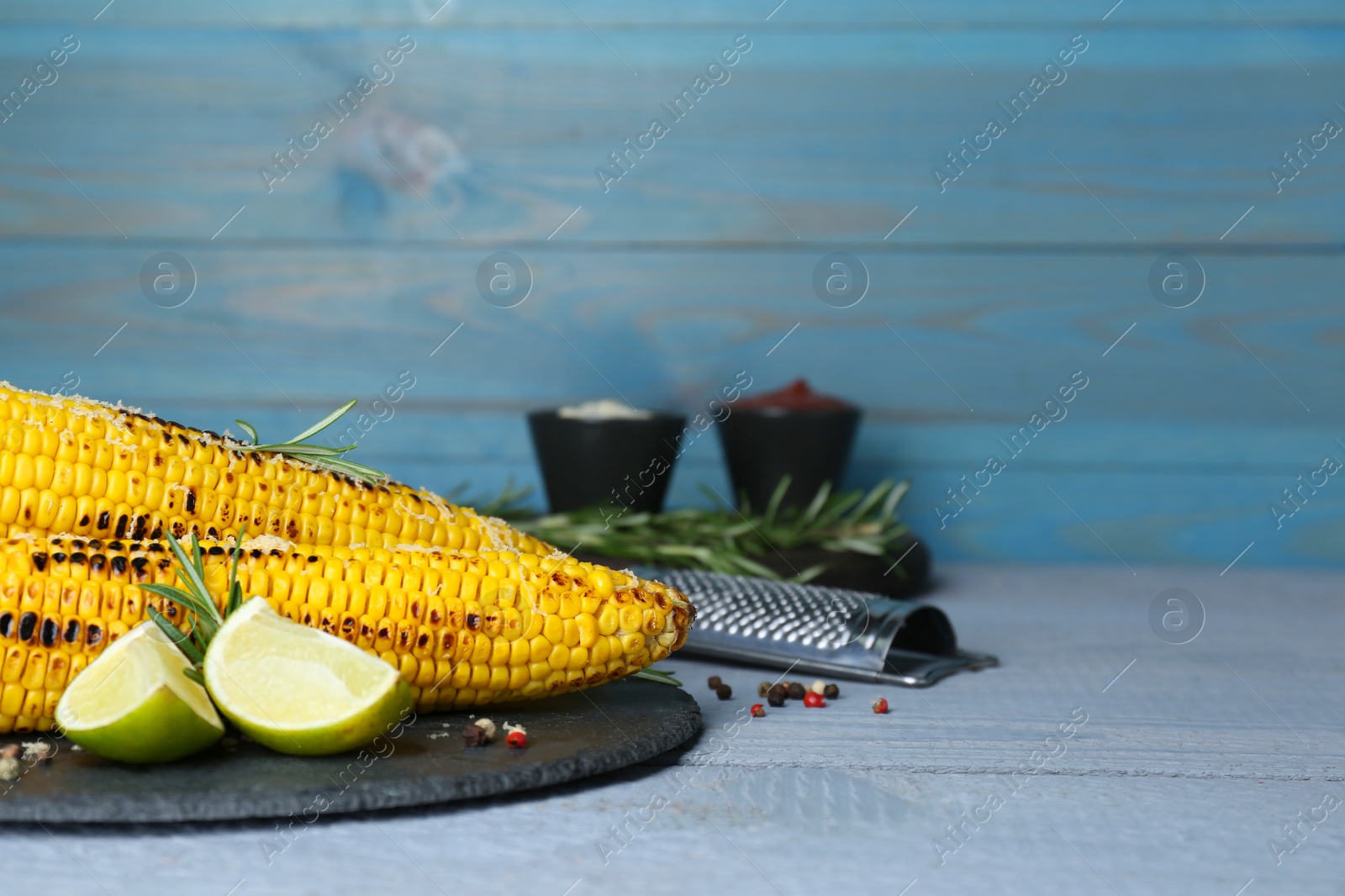 Photo of Tasty fried corn, spices and ingredients on light blue wooden table. Space for text