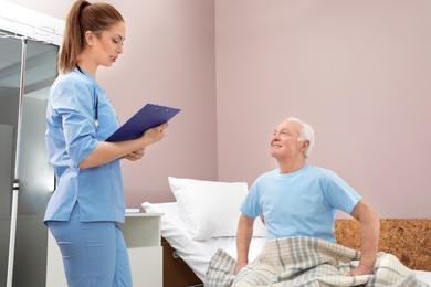 Nurse talking with senior man in hospital ward. Medical assisting