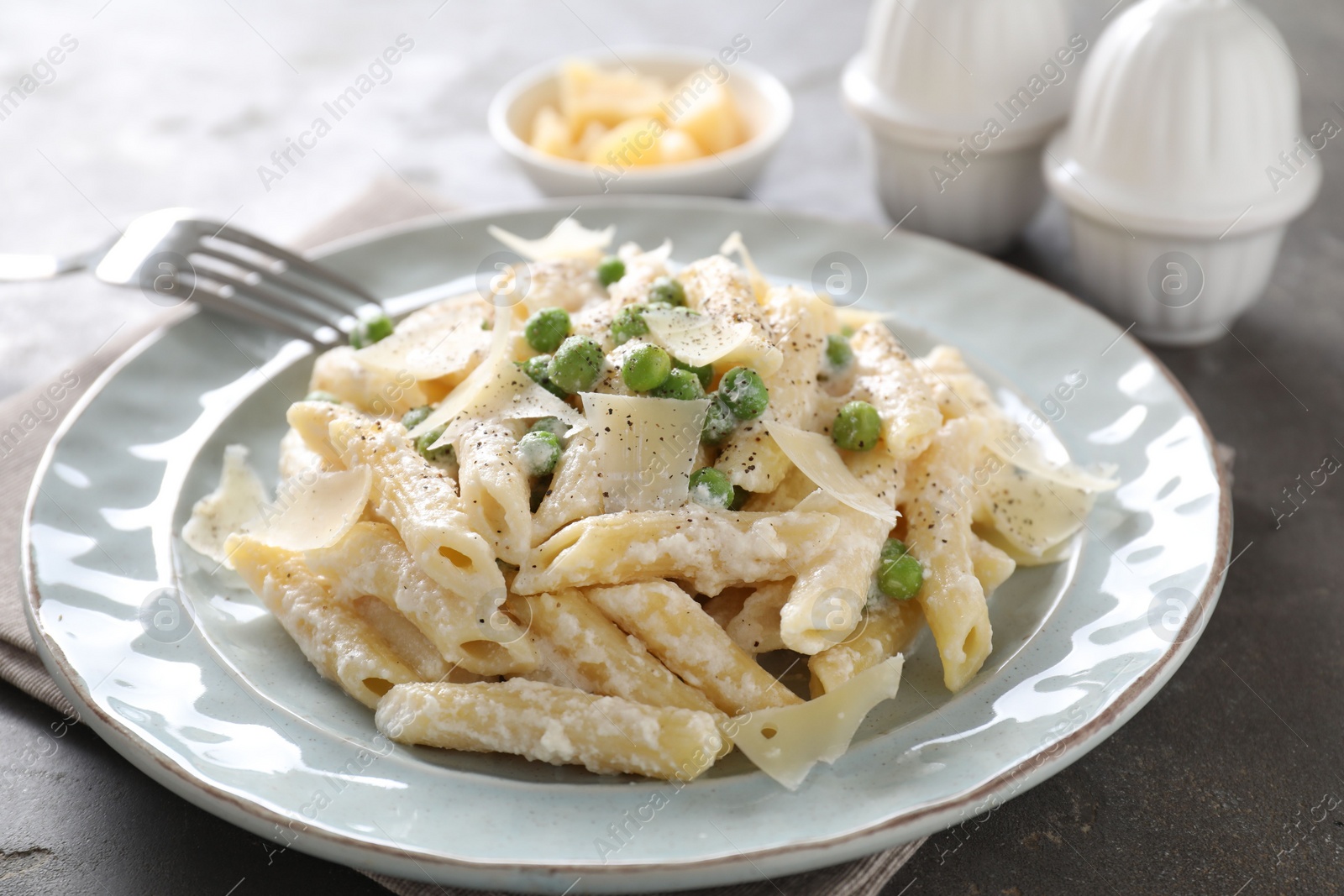 Photo of Delicious pasta with green peas, cheese and creamy sauce on grey table, closeup