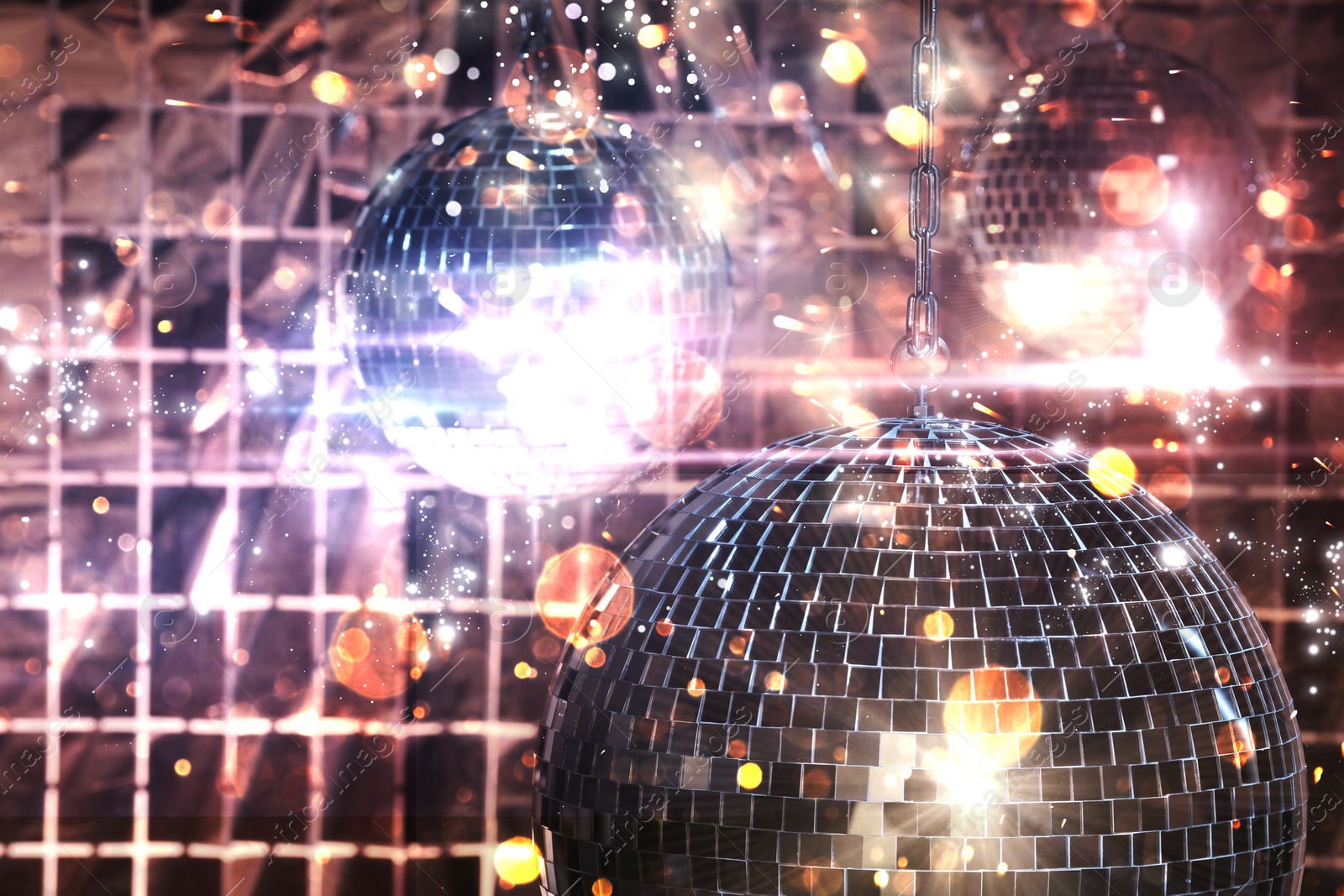 Image of Shiny disco balls against foil party curtain under color lights, bokeh effect