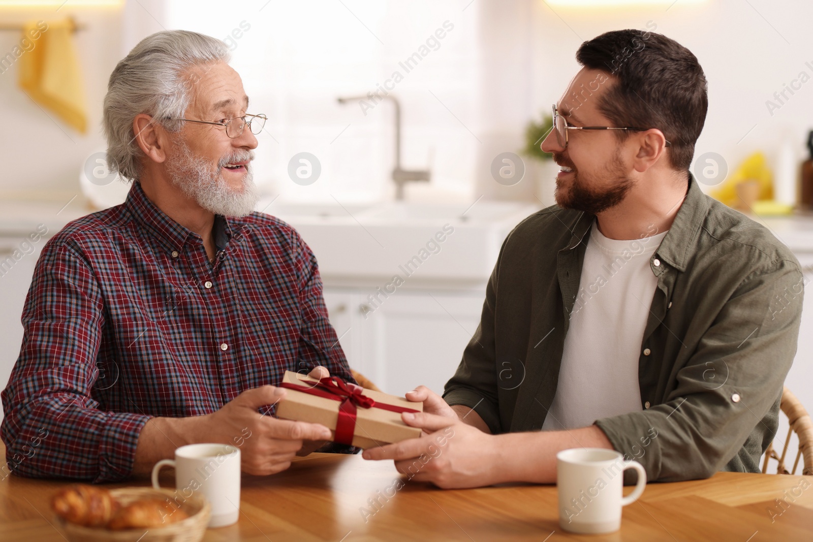 Photo of Son giving gift box to his dad at home