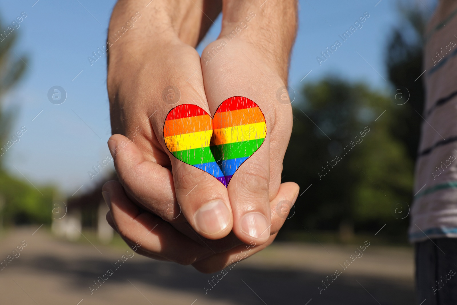 Image of Gay couple holding hands together in park on sunny day, closeup