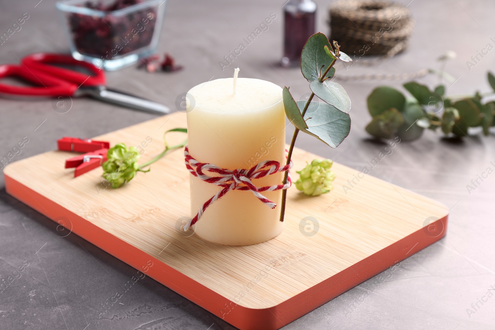 Photo of Handmade candle with eucalyptus on stone background