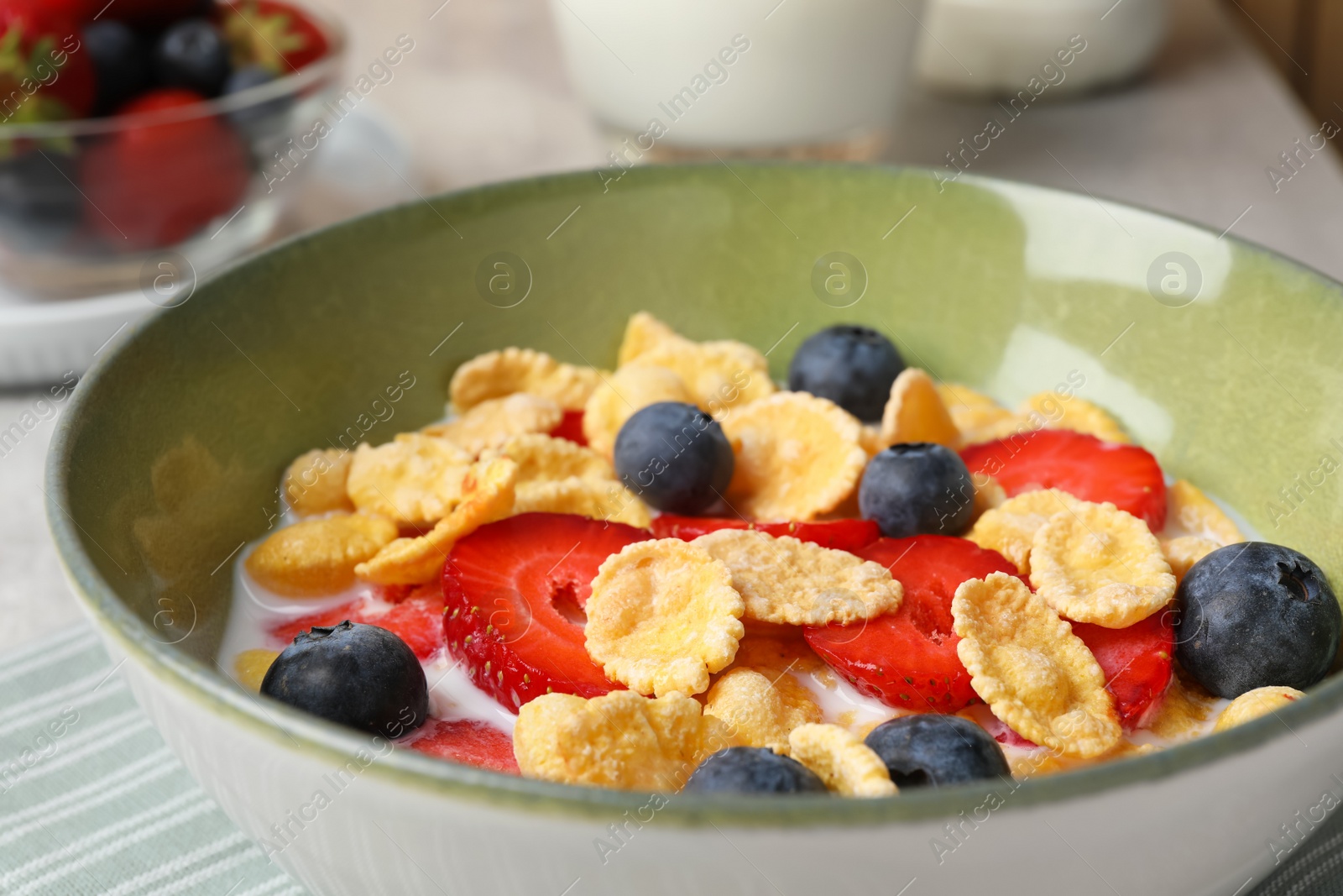 Photo of Corn flakes with berries in bowl served on grey table, closeup