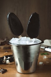 Photo of Glazed ice cream bars served in bucket on wooden table