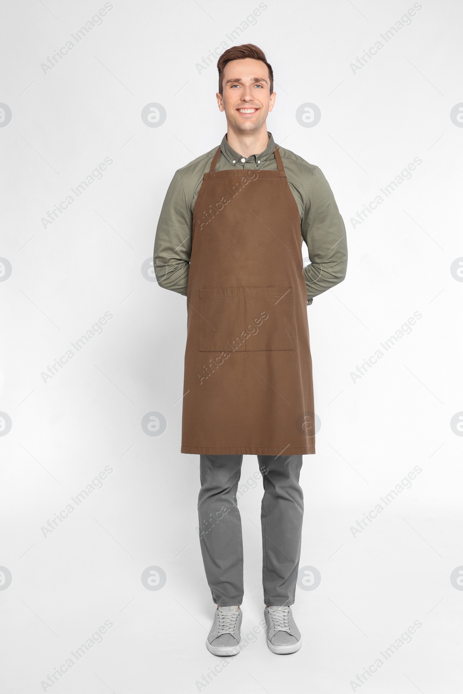 Photo of Full length portrait of handsome waiter in apron on light background