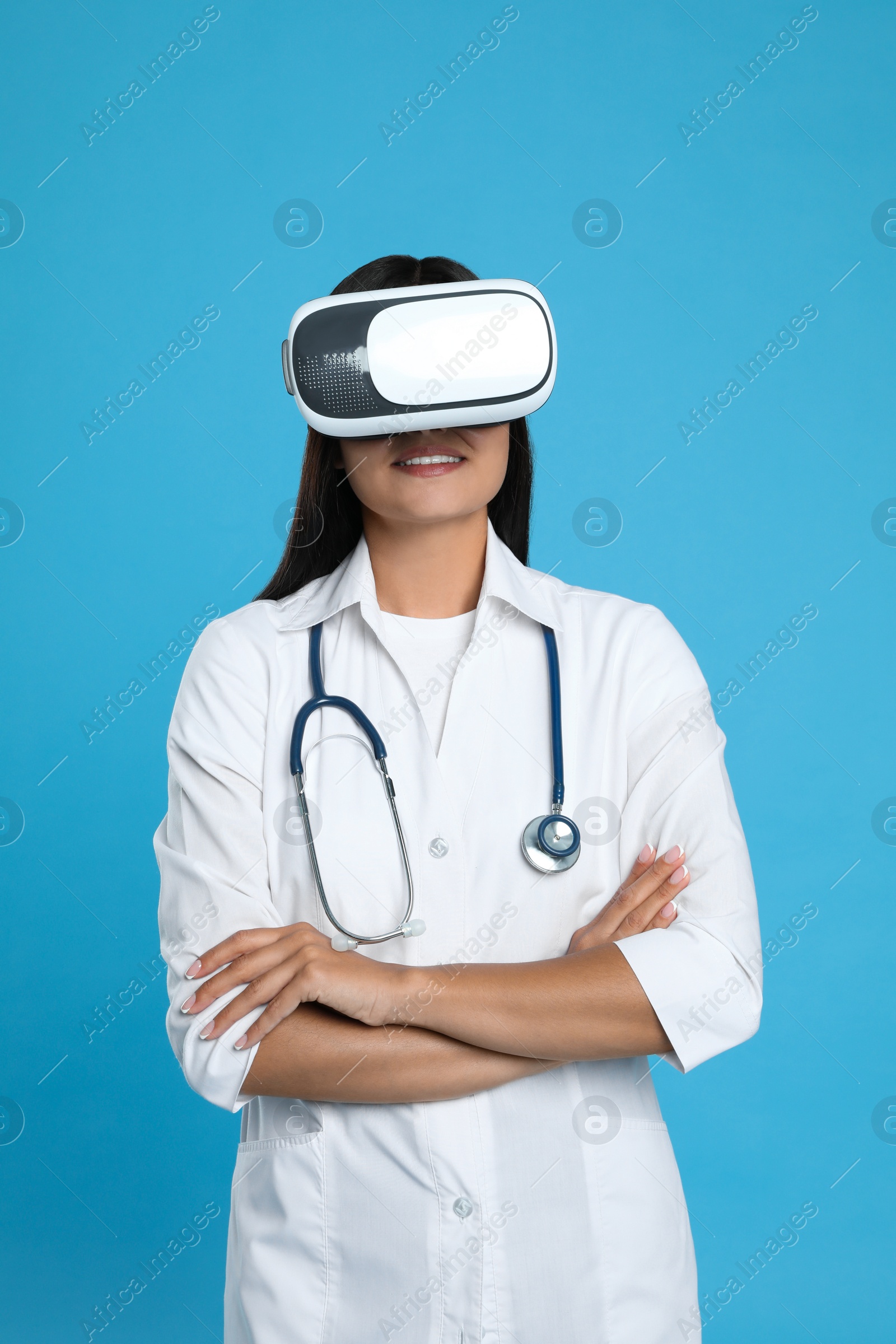 Photo of Female doctor using virtual reality headset on light blue background