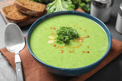 Photo of Tasty kale soup with pumpkin seeds on table, closeup