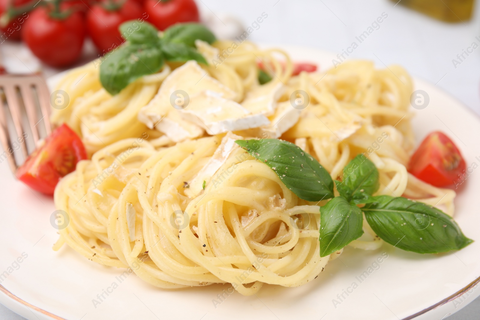 Photo of Delicious pasta with brie cheese, tomatoes and basil leaves on table, closeup