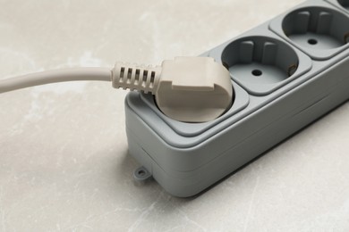 Photo of Power strip with extension cord on grey marble table, closeup. Electrician's equipment