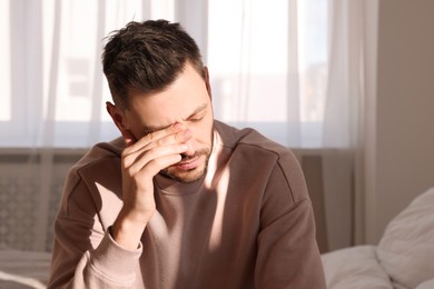 Photo of Upset man sulking at home, space for text. Loneliness concept