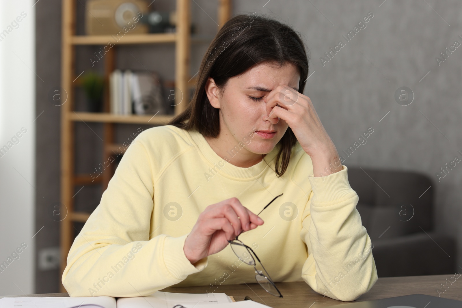 Photo of Overwhelmed woman with glasses at table indoors