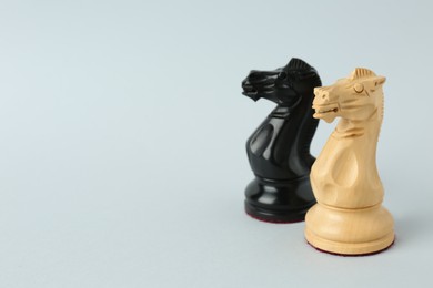 Photo of Black and white knights on light background, space for text. Chess pieces