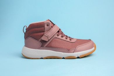 Photo of Stylish pink kid's sneaker on light blue background