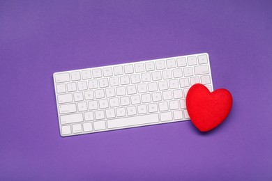 Photo of Long-distance relationship concept. Keyboard and decorative heart on violet background, top view