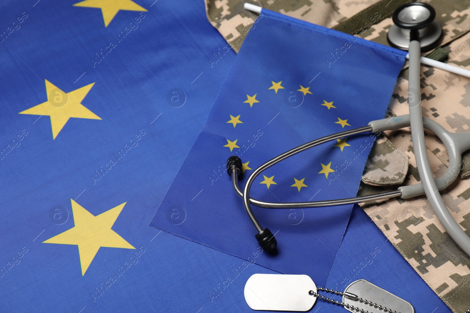 Photo of Stethoscope, tags and military uniform on flag of European Union, closeup