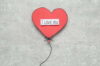 Heart shaped paper balloon with phrase I Love you on grey table, top view
