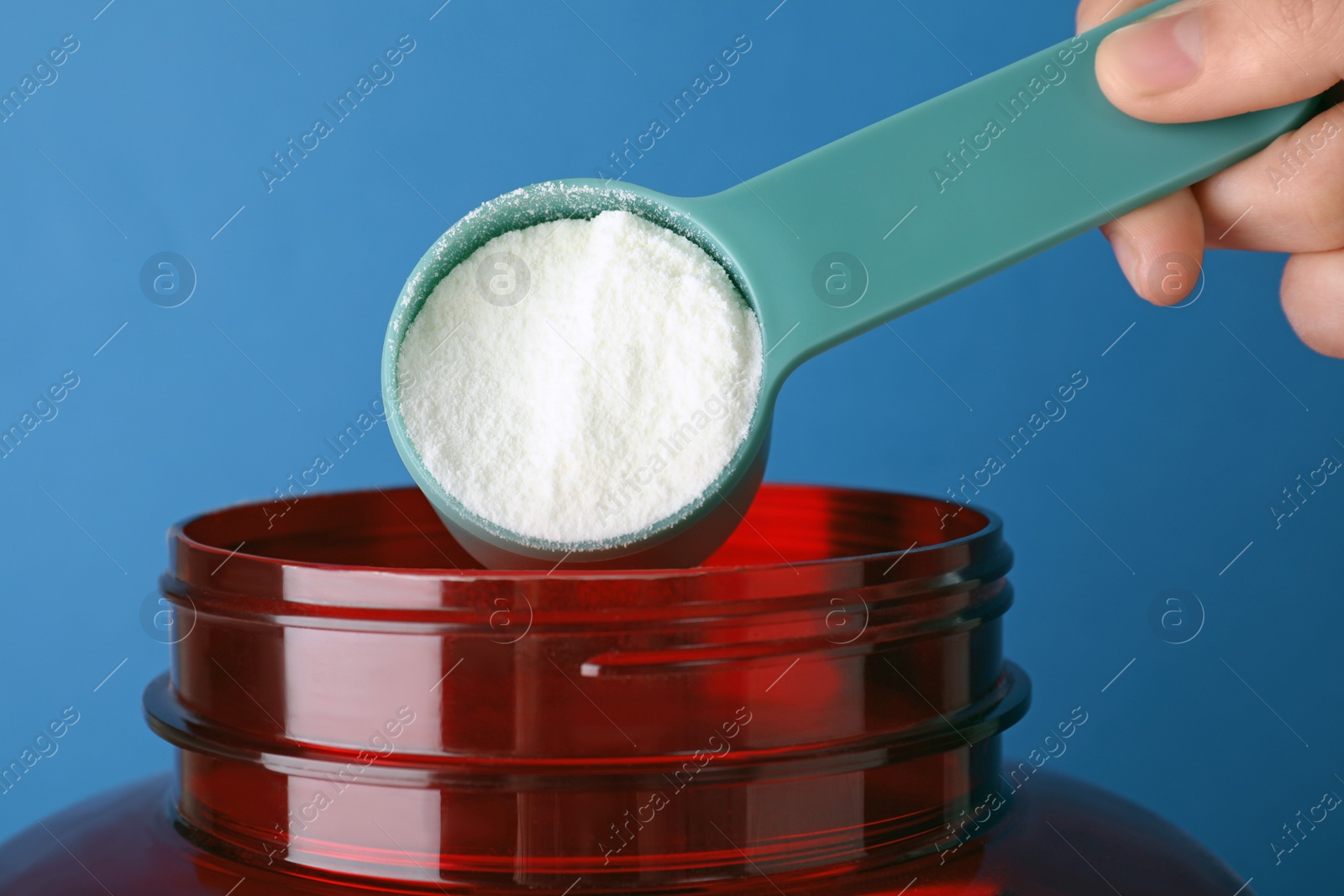 Photo of Man taking protein powder with scoop from jar against color background, closeup