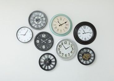 Photo of Many different clocks hanging on white wall.