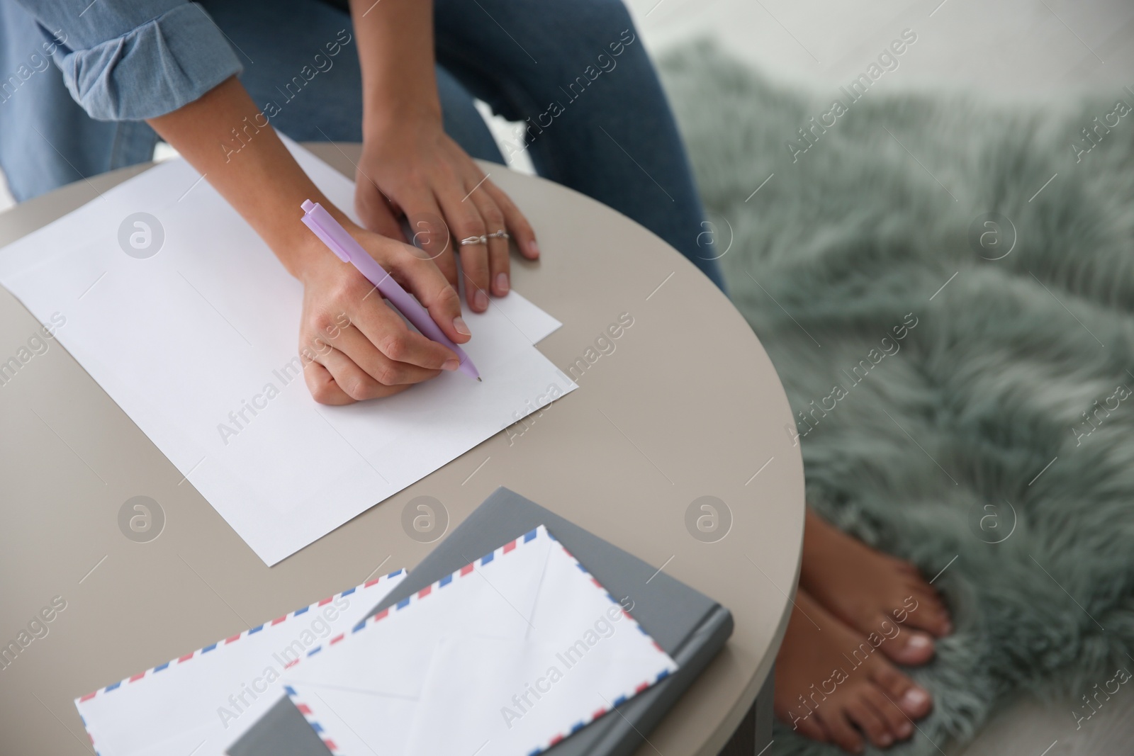 Photo of Woman writing letter at table indoors, closeup