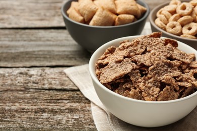 Photo of Different breakfast cereals in bowls on wooden table, closeup. Space for text